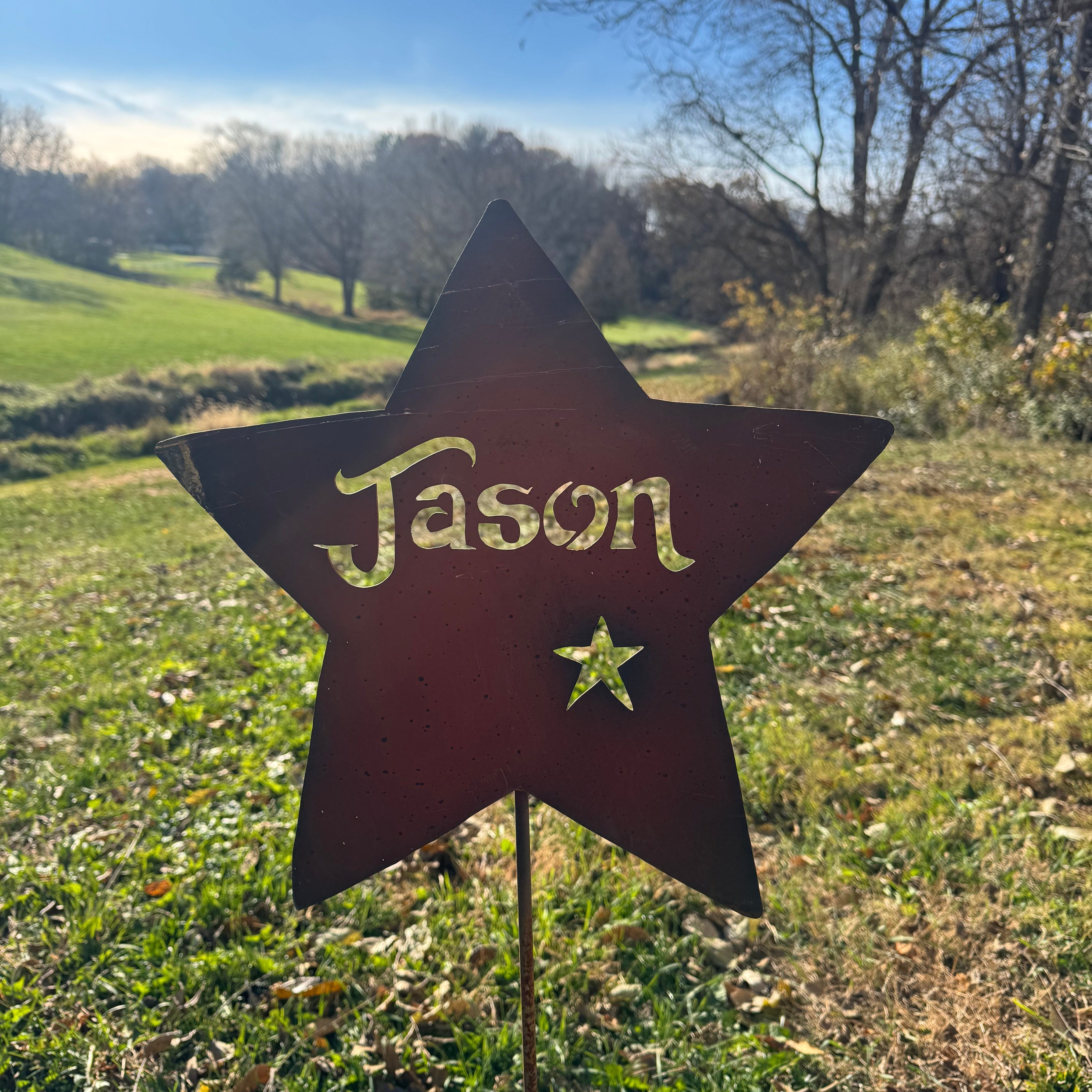 Star-shaped metal sign with 'Jason' on it in a grassy outdoor setting