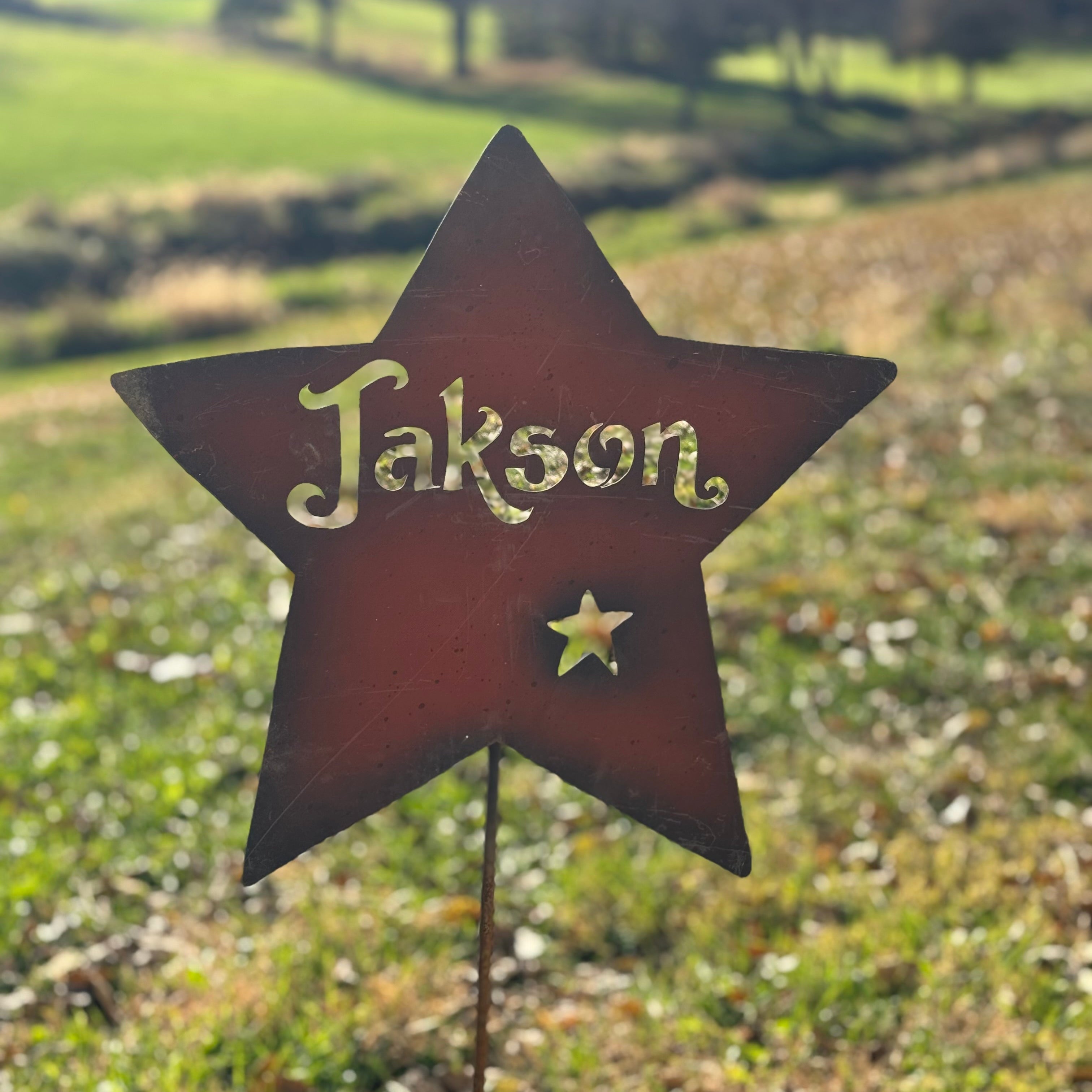 Star-shaped garden sign with 'Jakson' on a grassy background