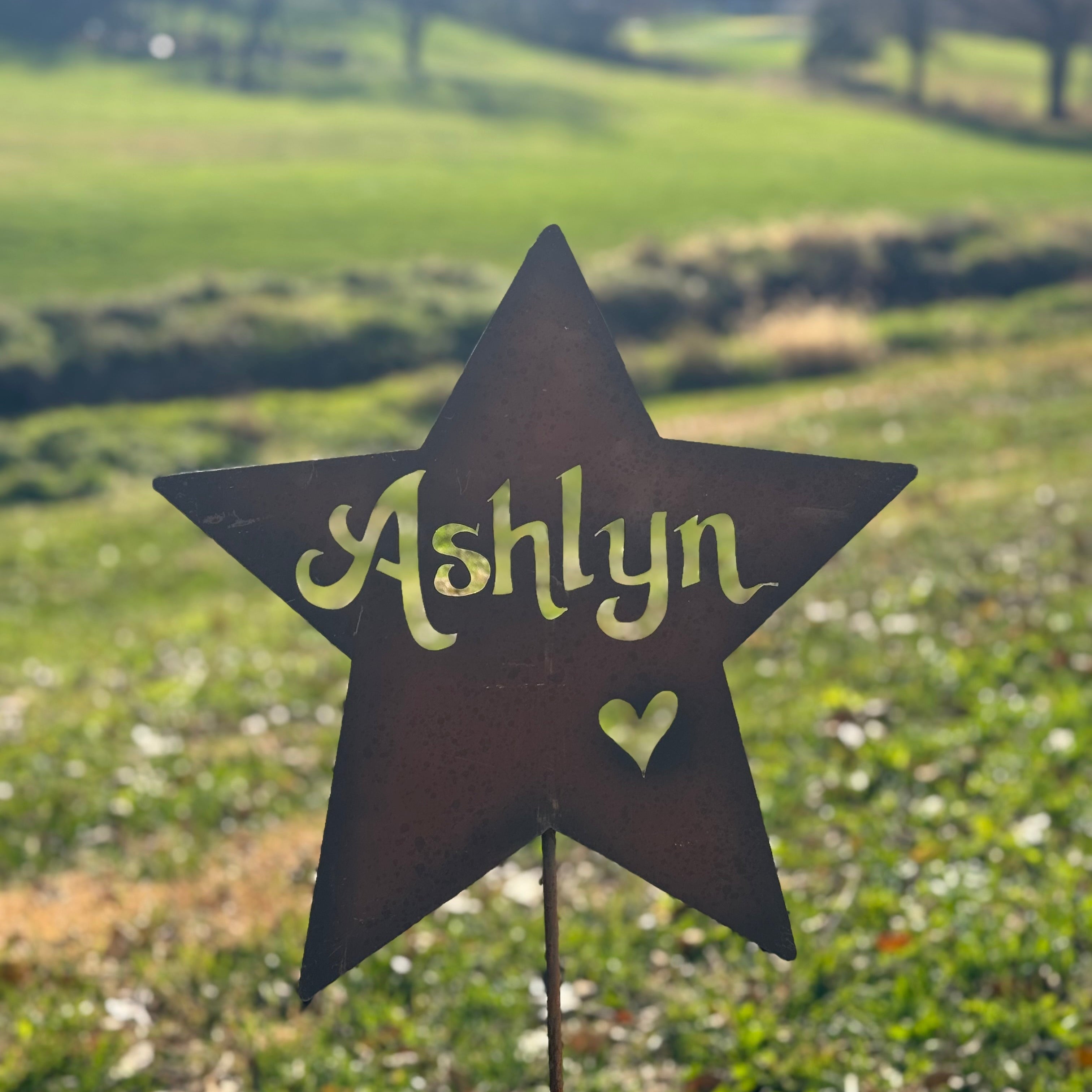 Star-shaped sign with 'Ashlyn' and a heart on a grassy field
