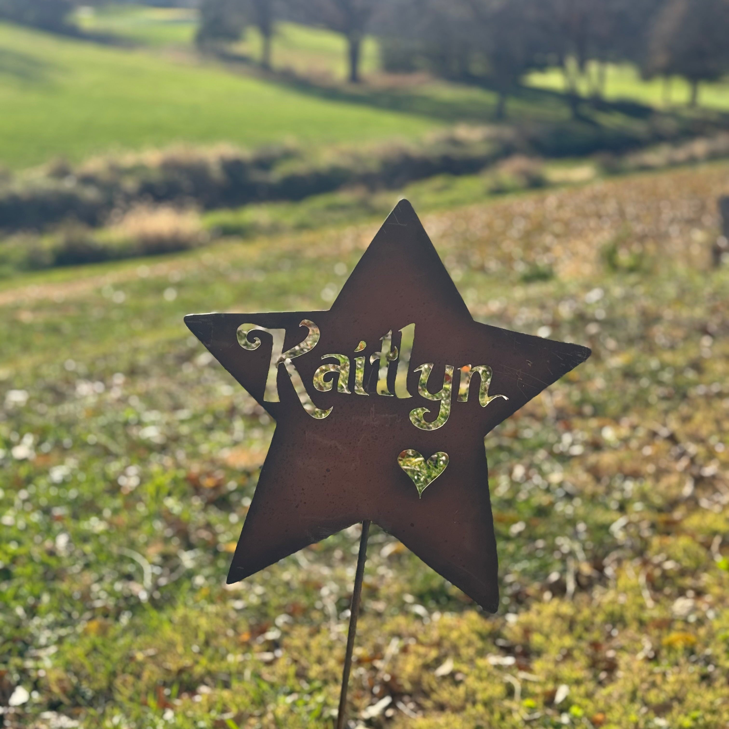 Star-shaped garden marker with 'Kaitlyn' on a grassy field