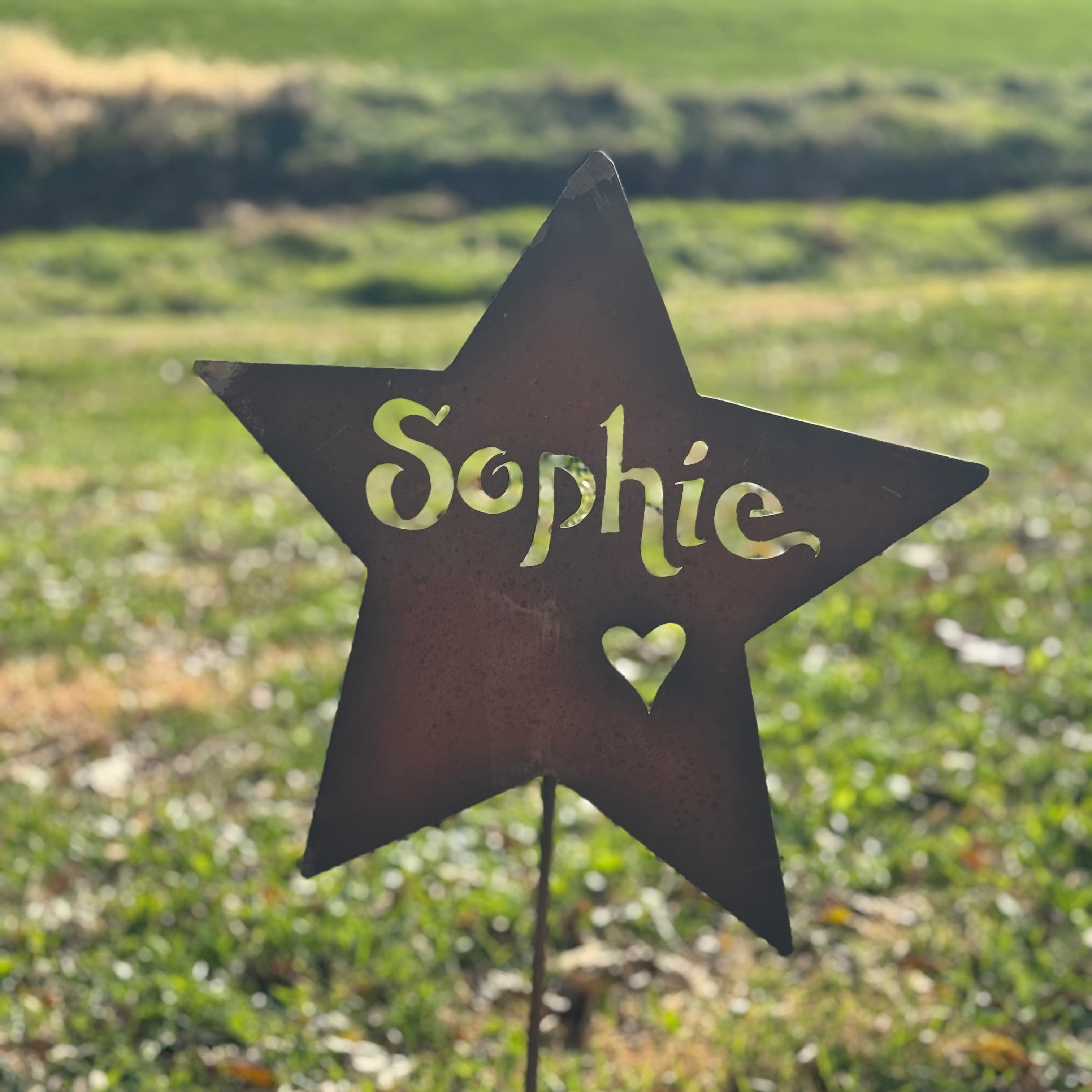 Star-shaped garden sign with 'Sophie' and a heart on a grassy background