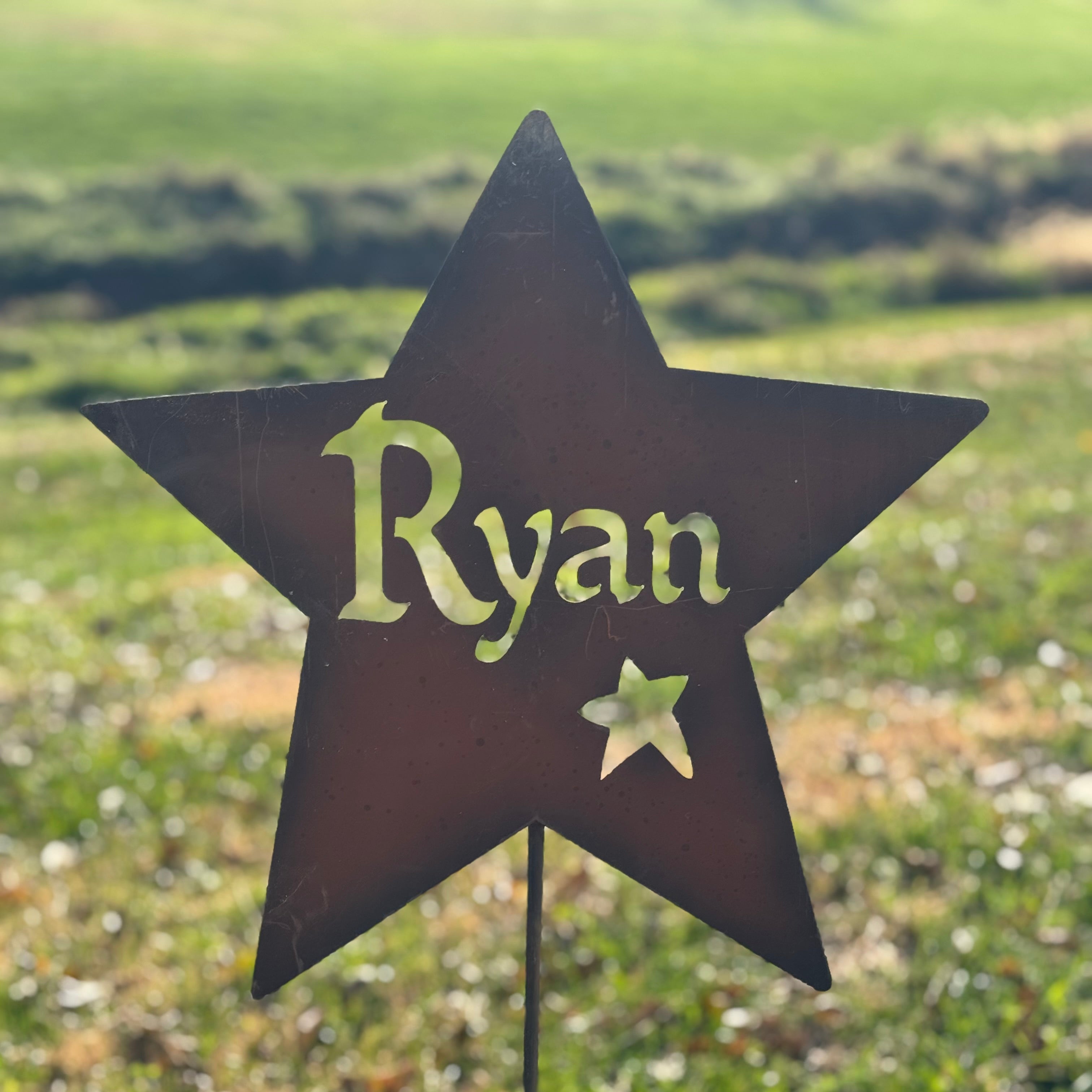 Star-shaped garden sign with 'Ryan' on a grassy background