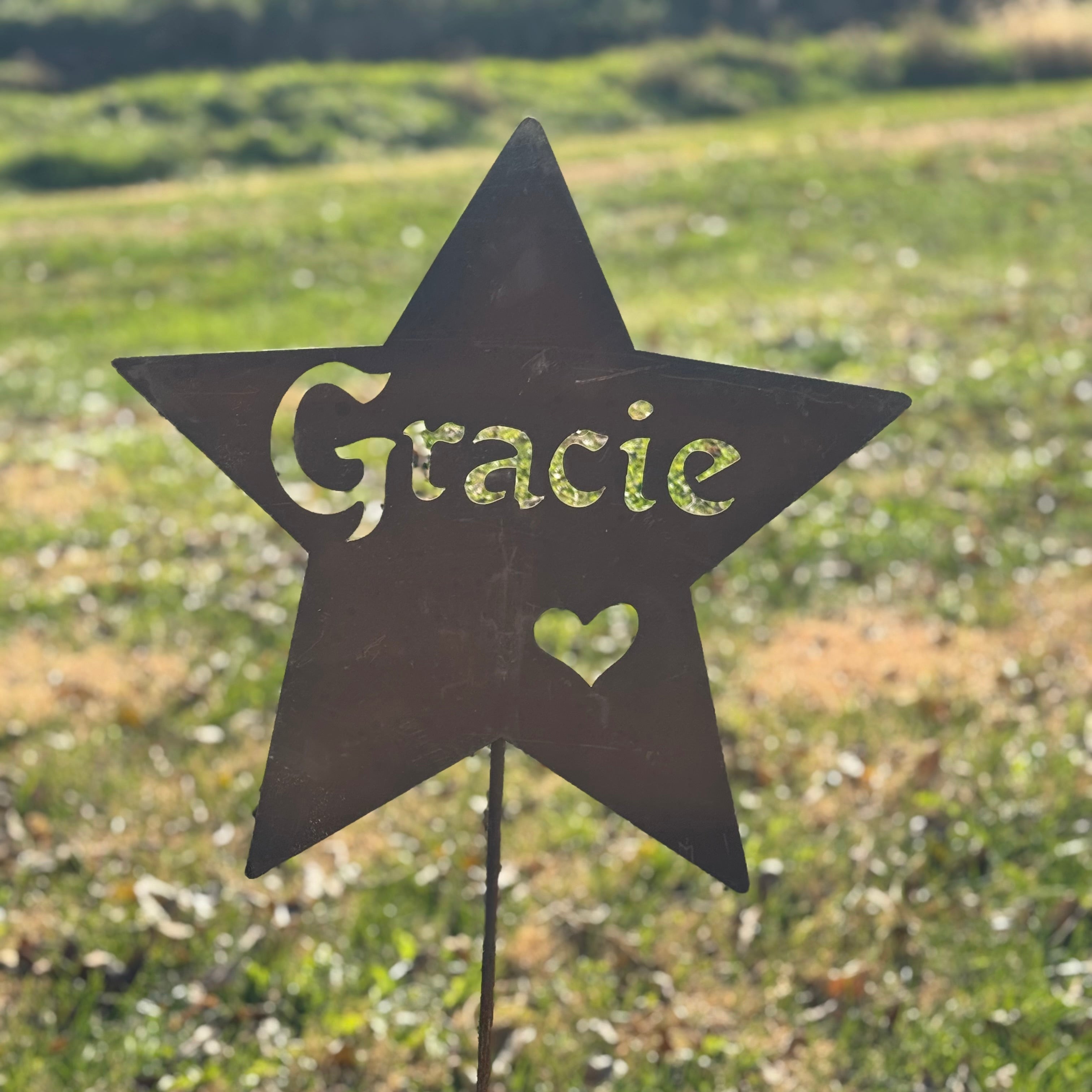 Star-shaped garden sign with 'Gracie' and a heart on a grassy background