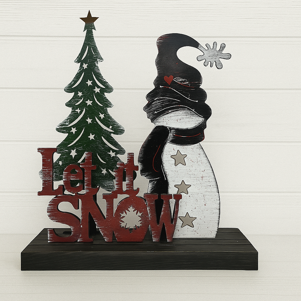 Decorative sign with a Christmas tree, snowman, and 'Let it Snow' text on a white wooden background.